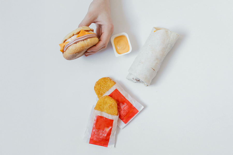 Ultra-processed food blog image of a classic fast food meal. Photo by Polina Tankilevitch: https://www.pexels.com/photo/person-holding-white-a-breakfast-sandwich-5848047/